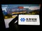 Person holding mobile phone with logo of Chinese mining company Huayou Cobalt Co. Ltd. on screen in front of web page.