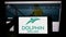 Person holding mobile phone with logo of company Dolphin Drilling Holdings Limited on screen in front of business web page.