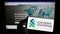 Person holding mobile phone with logo of financial company Standard Chartered plc on screen in front of business web page.