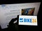Person holding mobile phone with logo of German bicycle e-commerce company Bike24 GmbH on screen in front of web page.