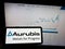 Person holding mobile phone with logo of German copper company Aurubis AG on screen in front of business web page.