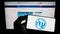 Person holding mobile phone with logo of International Telecommunication Union (ITU) on screen in front of web page.