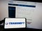 Person holding mobile phone with logo of Russian pipeline company Transneft JSC on screen in front of business web page.