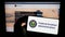 Person holding mobile phone with seal of American Federal Aviation Administration (FAA) on screen in front of web page.