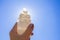 Person holding naturally carved mineral stone Selenite tower against sun and blue sky.