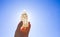 Person holding naturally carved mineral stone Selenite tower against sun and blue sky, stone has healing and cleansing properties.