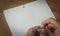 Person holding a pen over blank white paper