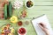 Person holding pencil and writing recipe in cookbook while cooking