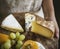 Person holding a platter of green grapes and different types of cheese