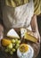 Person holding a platter of green grapes and different types of cheese