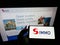 Person holding smartphone with logo of Austrian real estate investment company S IMMO AG on screen in front of web page.