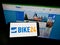 Person holding smartphone with logo of German bicycle e-commerce company Bike24 GmbH on screen in front of website.