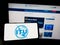 Person holding smartphone with logo of International Telecommunication Union (ITU) on screen in front of website.