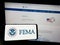 Person holding smartphone with seal of Federal Emergency Management Agency (FEMA) on screen in front of website.