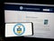 Person holding smartphone with seal of the United States Department of Commerce (DOC) on screen in front of website.