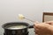 Person holding a spoon with porridge over the black cooker