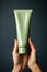 A person holding a tube of green cream. Beauty product mockup.