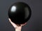 Person is holding up an inflated black balloon. The balloon has been deflated and appears to be empty inside. It\\\'s