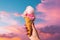 a person holding up a pink ice cream cone in the sunny sky, in the style of lush colors, eye-catching composition