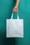 A person holding a white bag in their hand. Generative AI image. Blank tote bag mockup.
