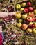 Person Holding a Yellow Apple in Front of a Basket of Apples