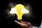 Person holding a yellow light bulb with cloud sketches AI generated