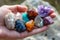 A person holds a collection of rocks in their hand, showcasing the diverse shapes, colors, and textures of the stones, A hand