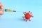 Person holds syringe with vaccine near red model of virus