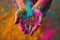 A person holds their hands tightly together, their palms filled with vibrant, powdered pigments, A splash of vivid colors