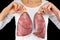 Person holds two lung models in front of white chest