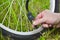 A person is inflating a bicycle wheel with the help of compressed air and a pressure gauge. Wheel and hand seen in the background