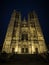 Person infront of illuminated facade of gothic catholic church cathedral of St Michael and St Gudula in Brussels Belgium