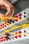 A person inserts a yellow black fiber optic cables into a switch. Hands close up. Vertical orientation.