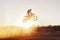 Person, jump and motorcyclist with sunset for trick, stunt or ramp on mockup or outdoor dirt track. Expert rider on