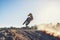 Person, jump and sports motorcyclist in the air for trick, stunt or race on outdoor dirt track. Rear view of expert