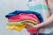 person in the laundry holding the stack of color clean towels