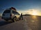 Person leaning against white vehicle SUV watching the spectacular sunset in the Salar de Uyuni