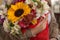 Person in leather jacket holding a bouquet of flowers with a sunflower, roses