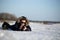 The person lies on the snow and the ice surface photographs. Landscape Photographer in a jacket with fur collar