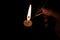 Person lighting a candle with a matchstick. Fingers with extinguished matchstick