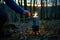 person lighting a portable camping stove in a forest at dusk