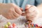 Person making earings from colorful beads and needles