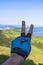 Person making the peace sign with a blue glove with the Jaizkibel mountain range on the background