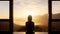A person meditates in silhouette against the stunning backdrop of a brilliant sunrise over scenic mountains and a