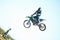 Person, motorcycle and air stunt in blue sky as professional in action, competition or fearless. Bike rider, off road