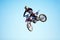 Person, motorcycle and jump adventure in blue sky as professional in action, competition or fearless. Bike rider, off