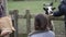 Person in next to a little girl, hand-feeding a black and white sheep