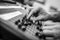 Person operating a mixing desk with their hands making adjustments to the knobs in grayscale