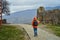 A person in an orange raincoat with a backpack walks in the rain in the mountains