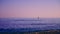 Person paddling a surfboard on the Mediterranean Sea during a sunset